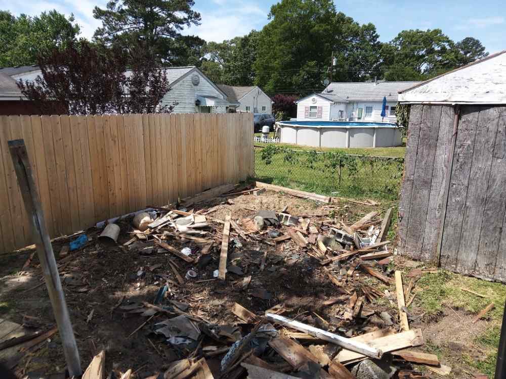 Scrap wood debris and concrete blocks on a residential backyard site after a shed demolition.