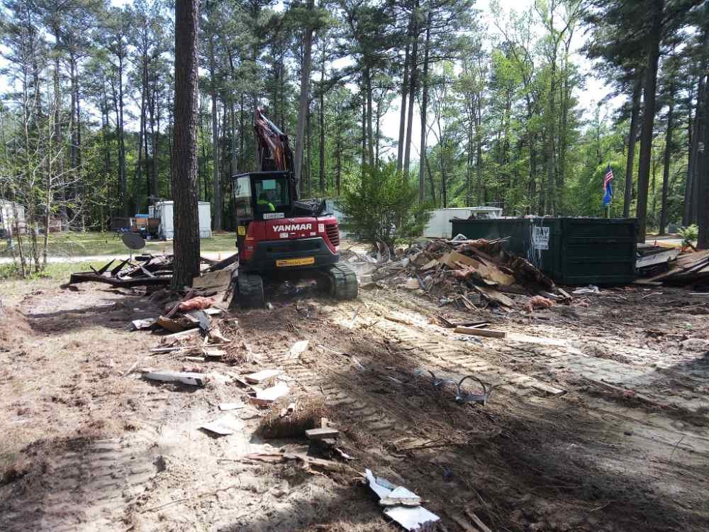 Yanmar excavator clearing debris and structural wreckage during a residential demolition and site cleanup project.