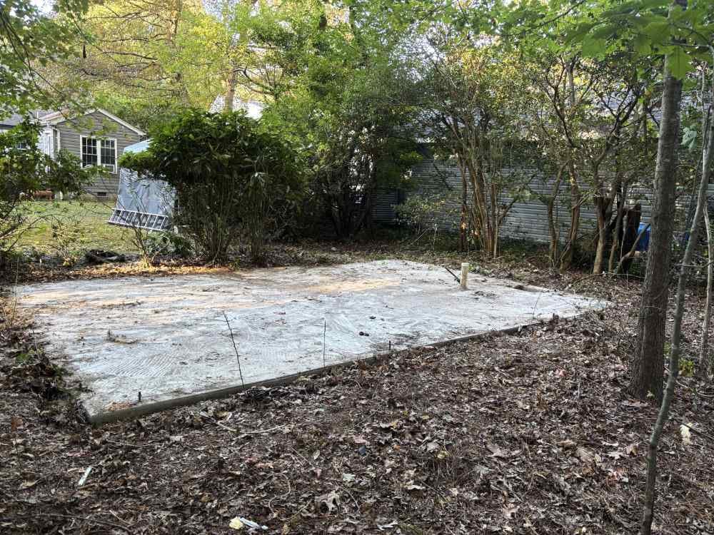 Concrete slab foundation cleared in a residential backyard after structure demolition and site cleanup.