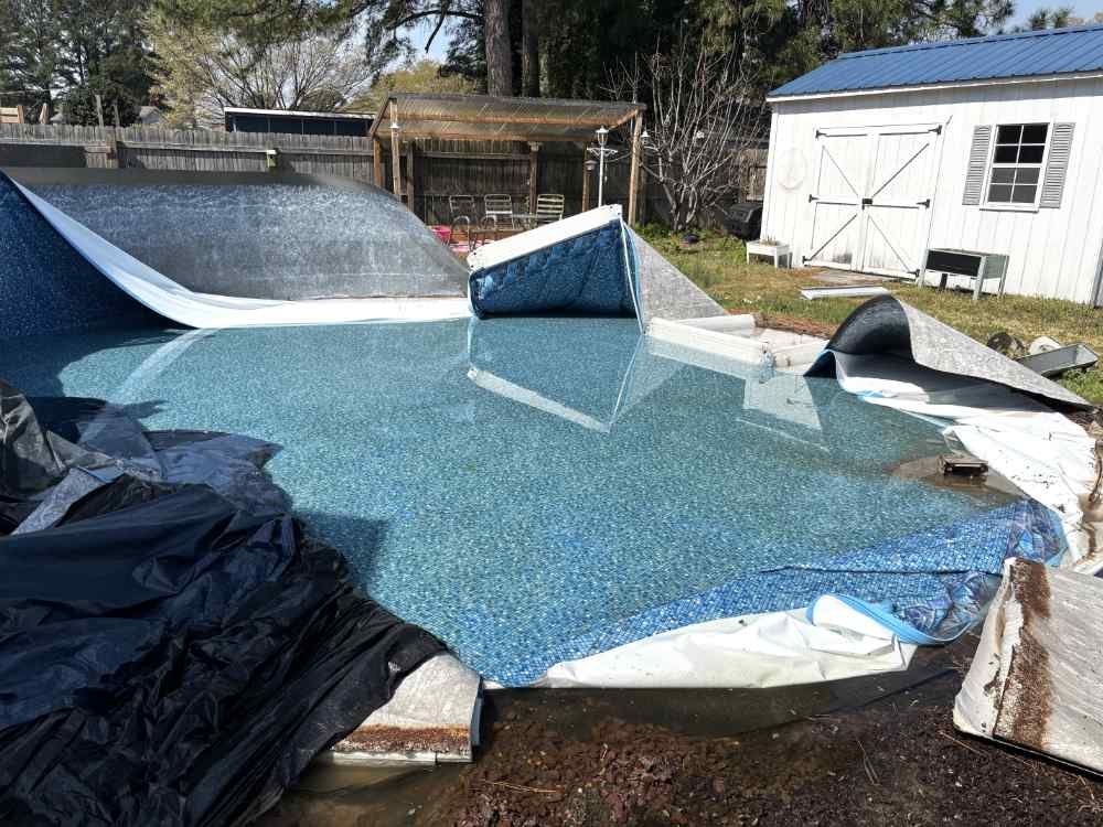 Residential backyard swimming pool demolition and liner removal in progress.