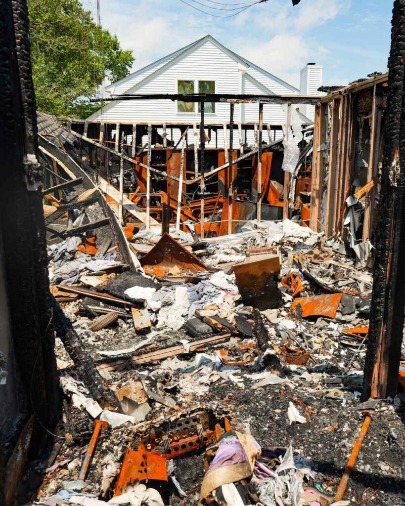Residential fire damage and debris pile ready for structural demolition and site clearing.