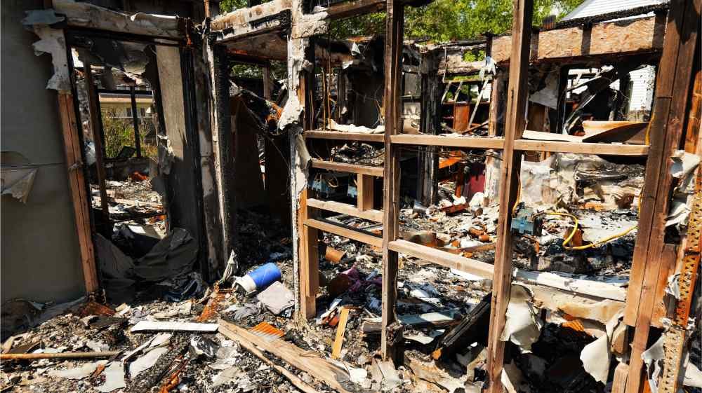 Residential demolition site showing interior framing and fire or structural debris ready for cleanup.