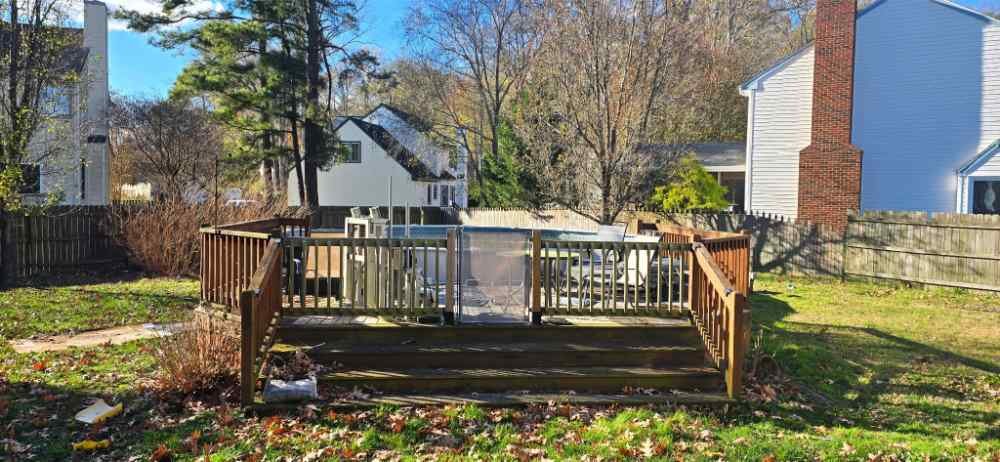 Residential backyard with an above-ground swimming pool and wooden deck scheduled for demolition and site clearing.