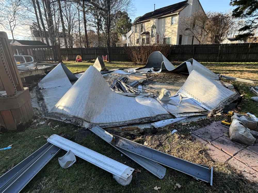 Residential backyard in-ground swimming pool demolition and removal project showing collapsed metal pool walls and debris.