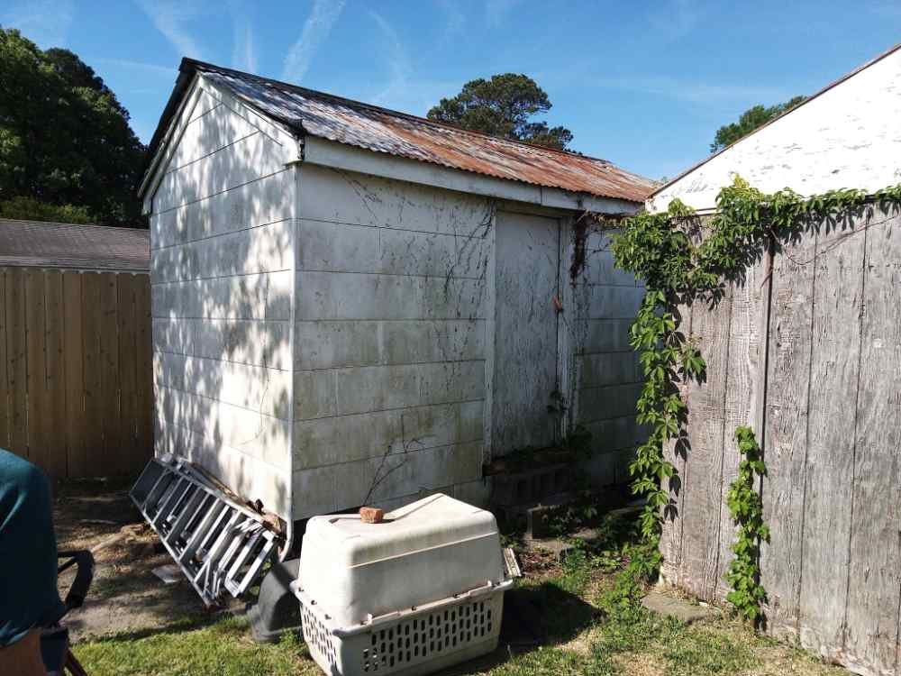 Old weathered backyard shed with a rusted metal roof ready for residential shed demolition and removal services.