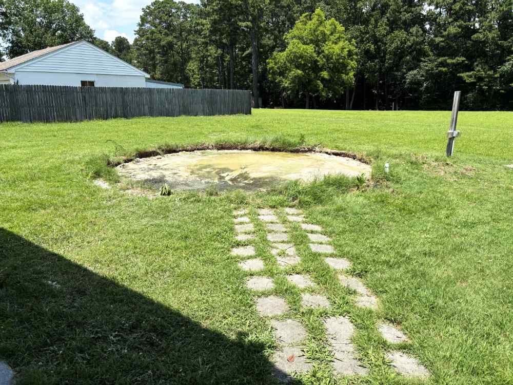 **Alt Text:**Cleared circular site in a residential yard following above-ground pool removal and site preparation services.
