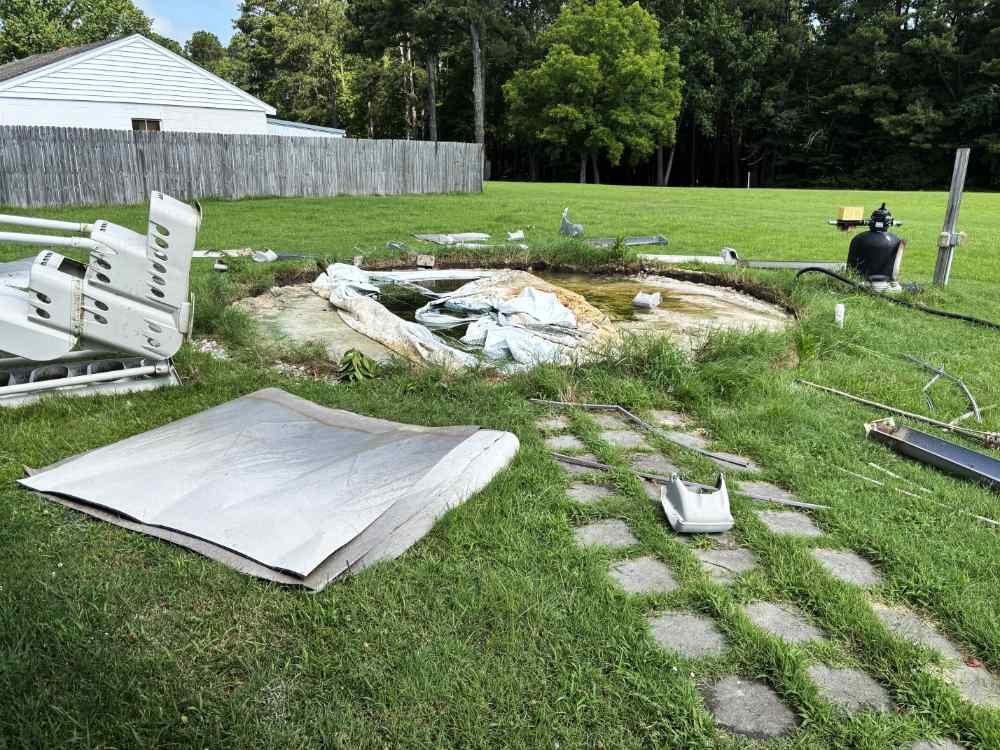Dismantled above-ground pool frame and torn liner during a residential pool removal and site clearing project.