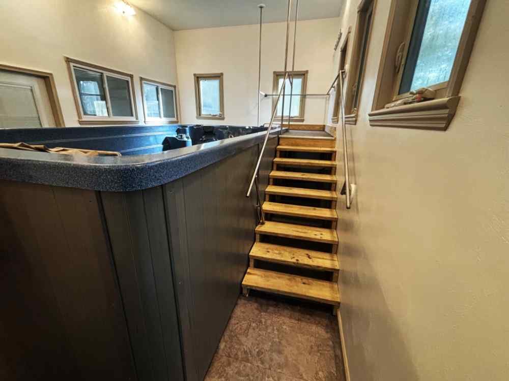 Indoor hot tub and wooden access stairs slated for residential interior demolition.