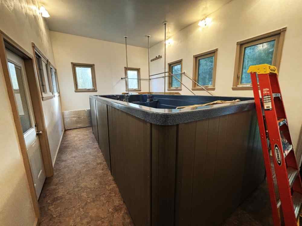 Indoor swim spa and hot tub removal preparation inside a residential room.