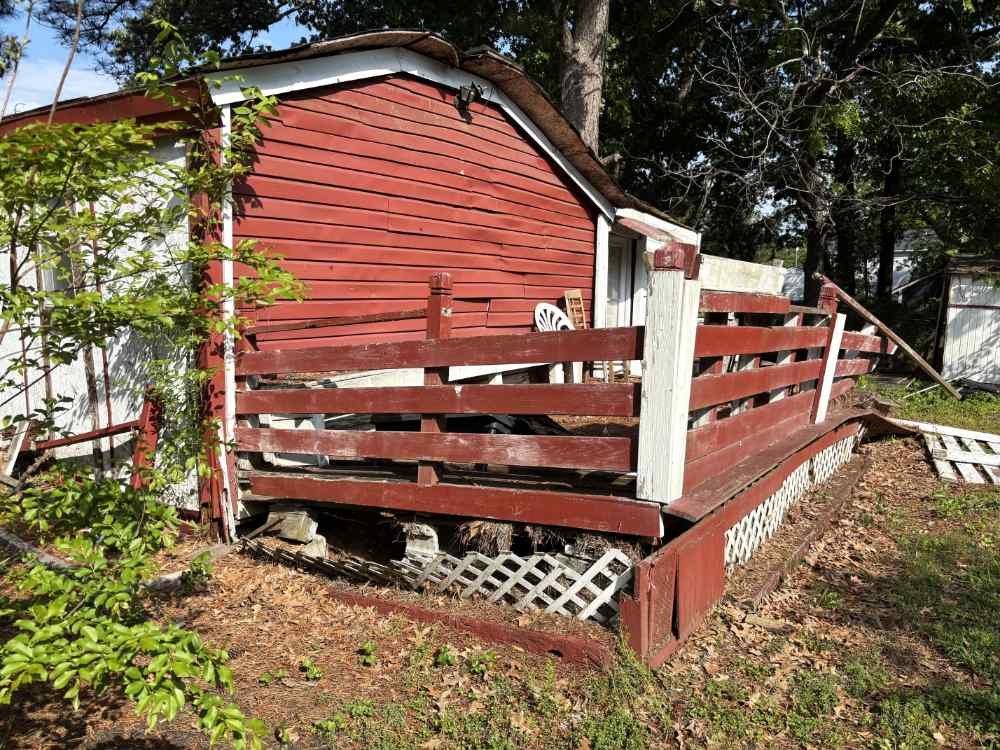 Damaged residential shed and wooden deck slated for demolition and site clearing.