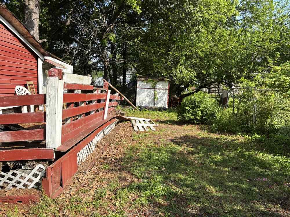 Residential backyard scheduled for shed demolition and deck removal site clearing.