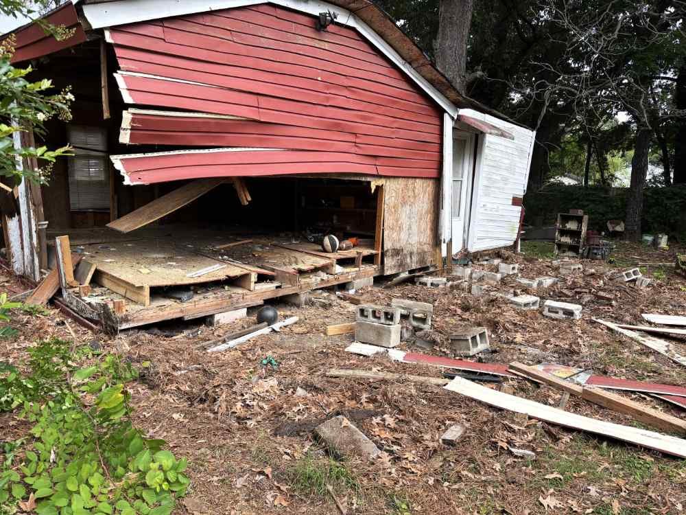Shed demolition in progress with partial wall removal and scattered wood debris on site.